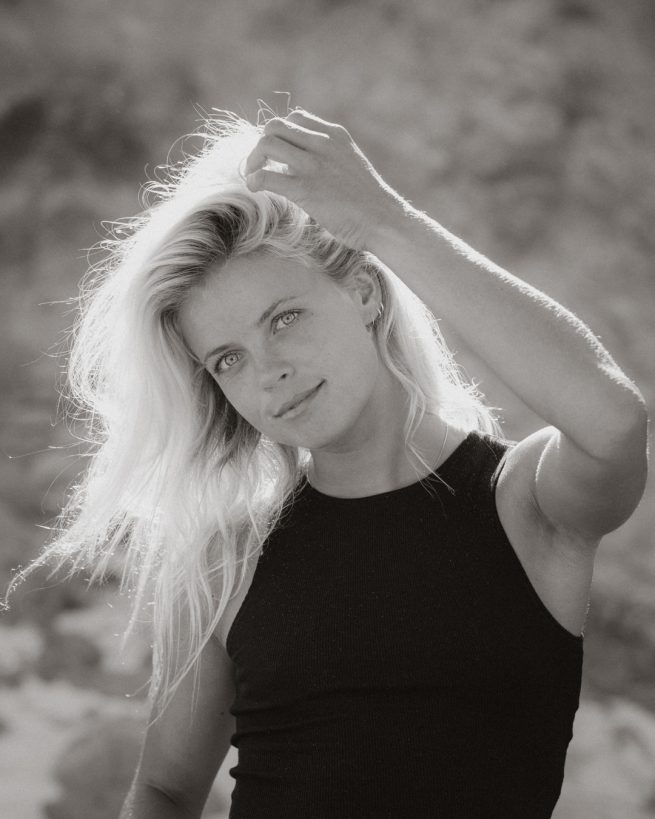 Profisurferin im Gegenlicht in den Dünen am Strand in Portugal