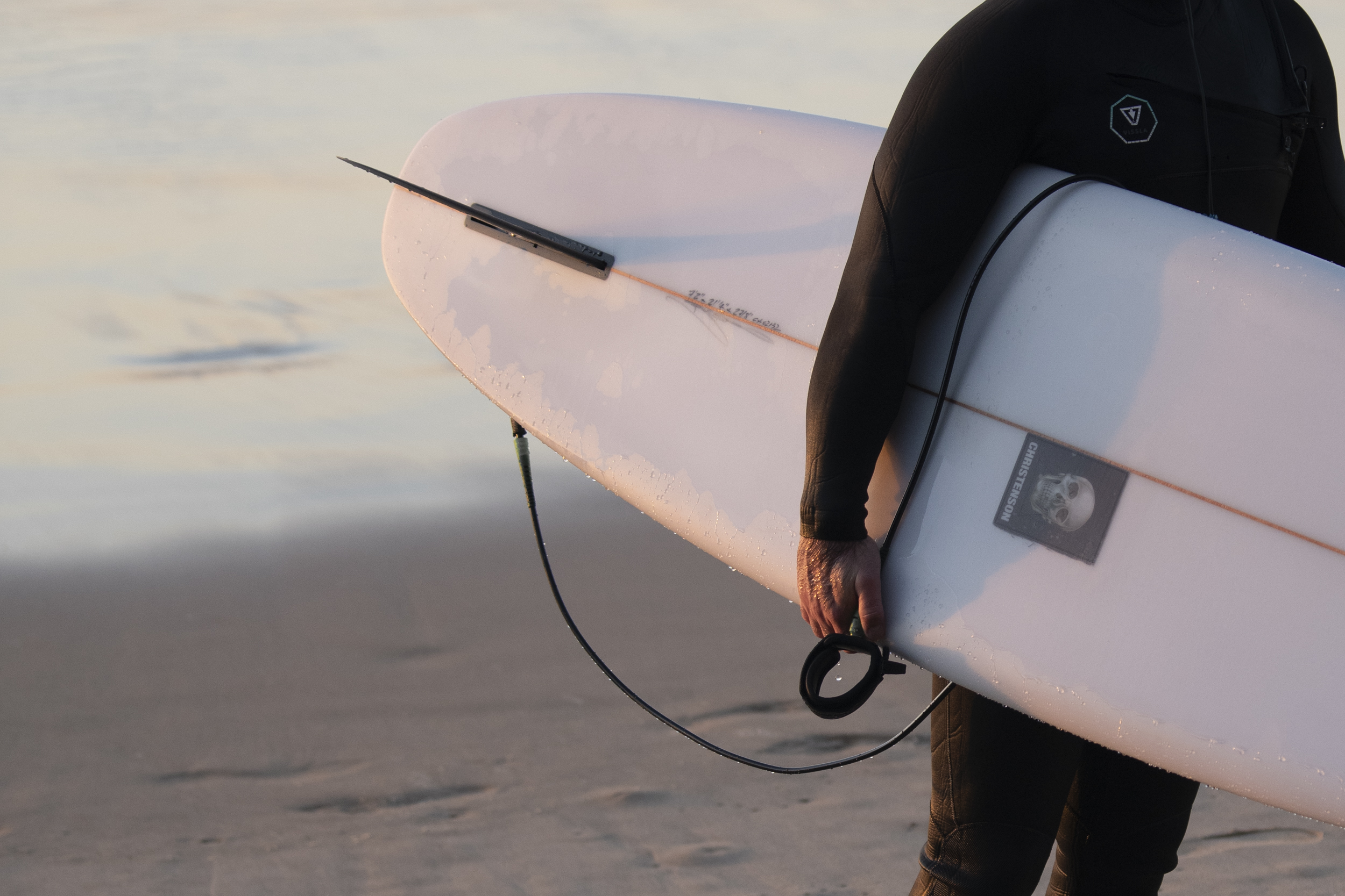 Mann trägt Surfbrett von Christensen.