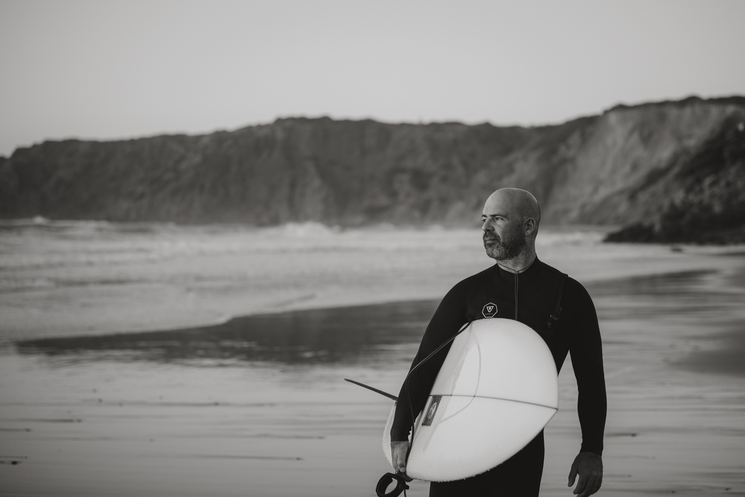 Surfer am Strand in Portugal schaut auf das Meer