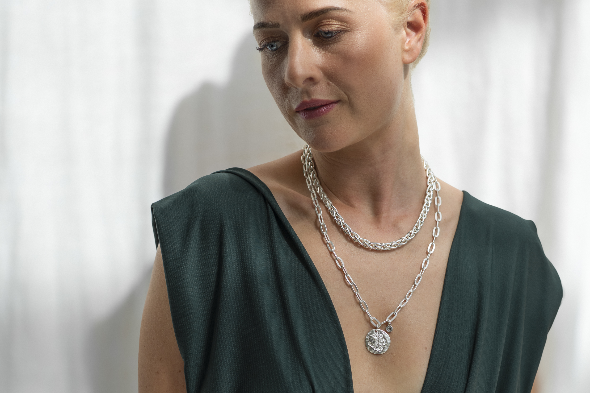 Rundeschmuck Stuttgart Commercial Frau steht mit dem Gesicht im Schatten, Licht fällt auf den Schmuck am Hals